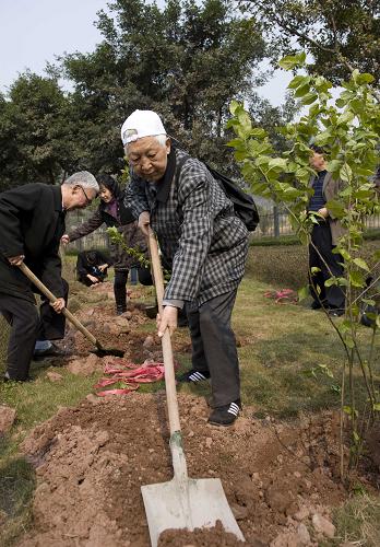 3月12日,82岁的老人赵国良(中)种下一棵樱桃树,他的前列腺癌还在治疗中。 当日,重庆市50名癌症患者在重庆渝北海扶园区种下寄托希望的樱桃树,祝福所有的癌症患者坚强地面对病痛,找回生命里的春天和希望。 新华社记者 杨磊 摄